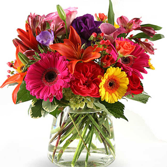 Mixed bouquet of bright flowers in a clear glass vase