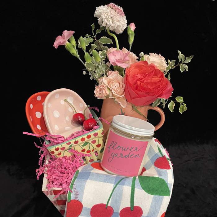 Gift basket with flowers, a cherry-print cloth, and a candle jar