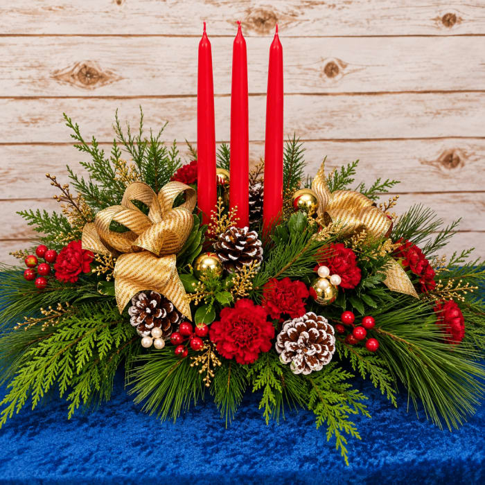Christmas centerpiece with red candles, pinecones, and gold ribbon