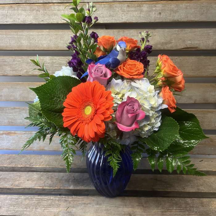 Colorful mixed bouquet in a blue vase with roses, hydrangea, and a gerbera daisy