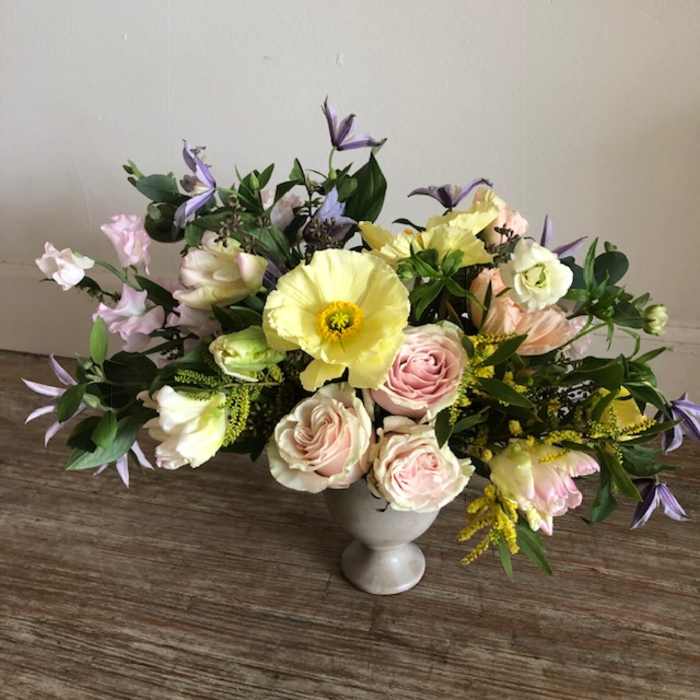 Pastel floral arrangement in a white vase with pink and yellow blooms