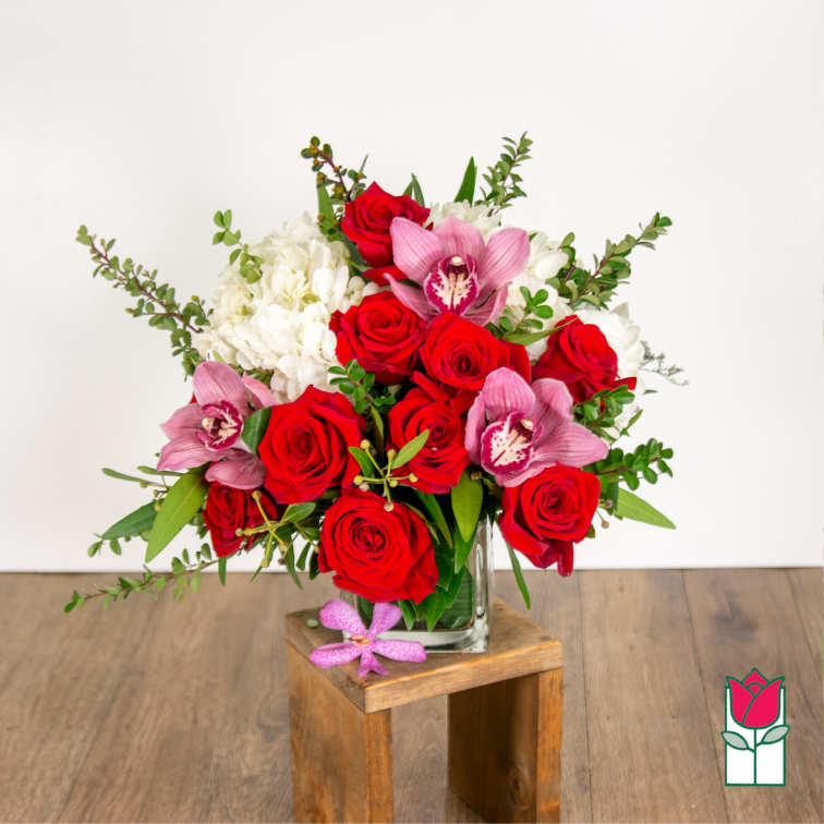 Bouquet of red roses, pink orchids, and white hydrangeas in a glass vase