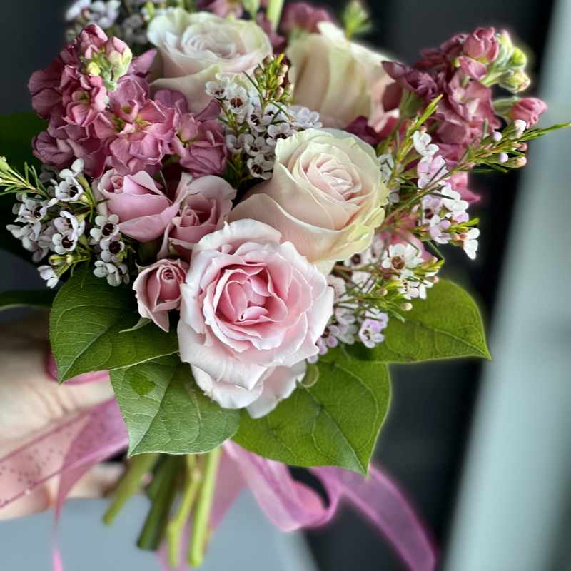 Hand-tied bouquet of pale pink roses and mauve flowers finished with a pink ribbon