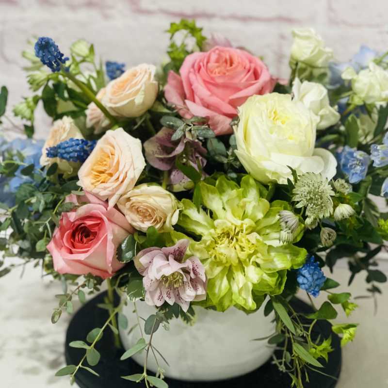 Mixed bouquet of pink, white, and blue flowers in a white vase