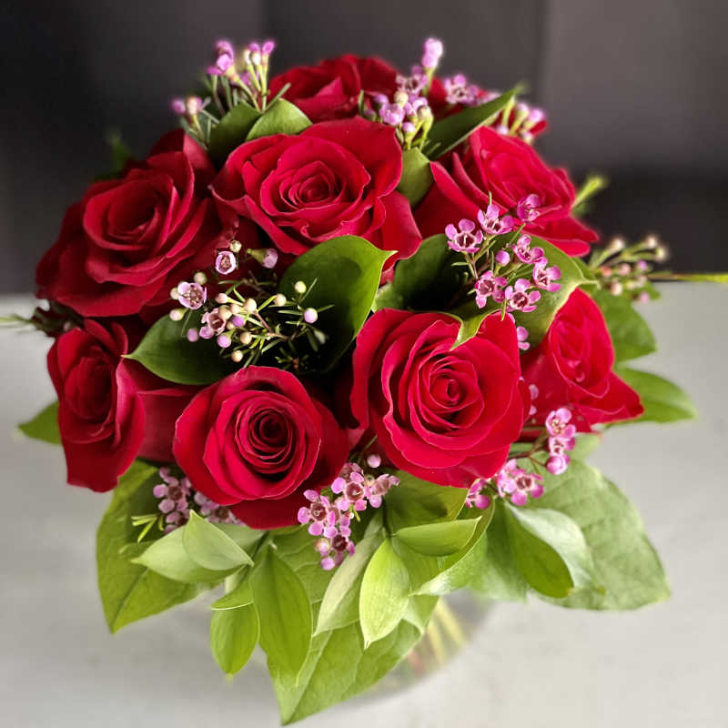 Bouquet of red roses with pink filler flowers in a clear vase