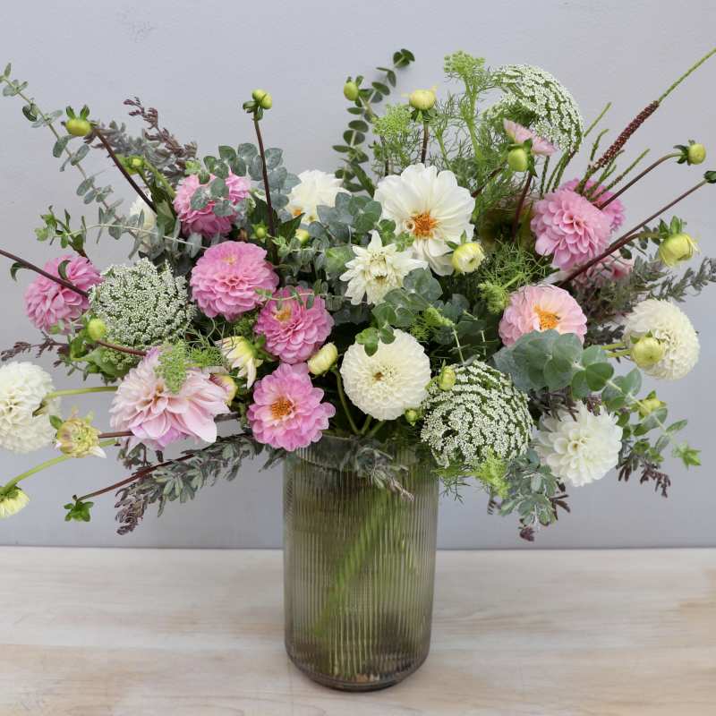Tall glass vase arrangement of pink and white dahlias with airy filler flowers