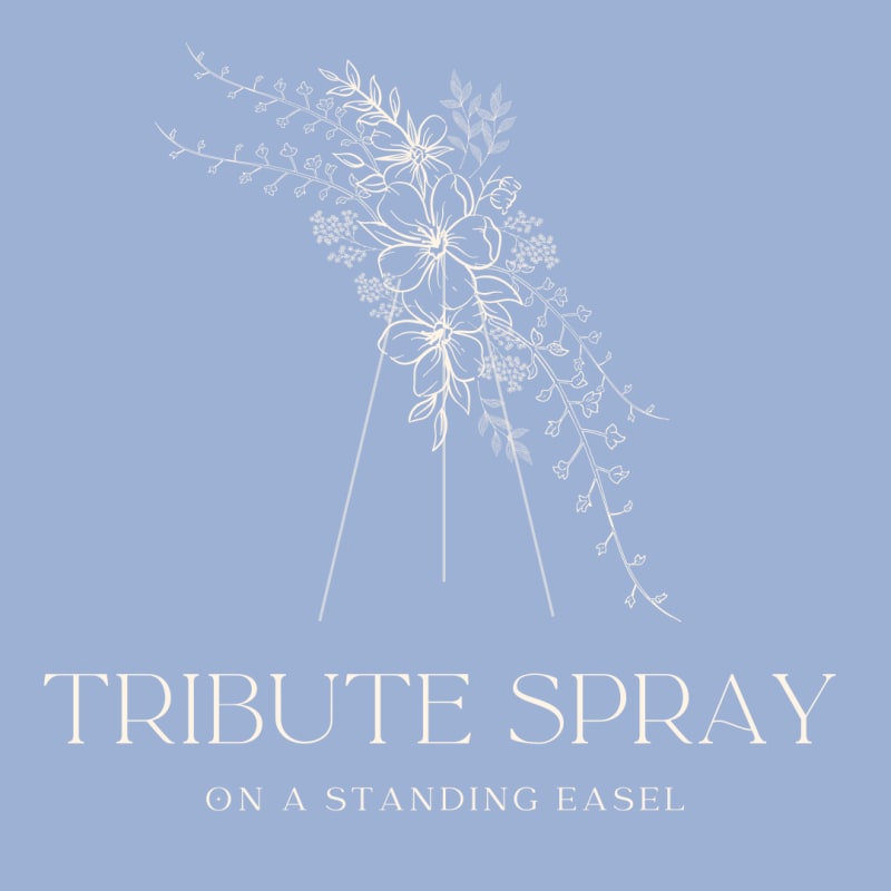 White floral tribute spray on a standing easel against a blue background
