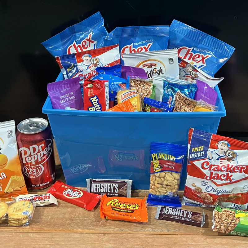 Gift basket with snack bags, candy bars, and soda cans in a blue bin