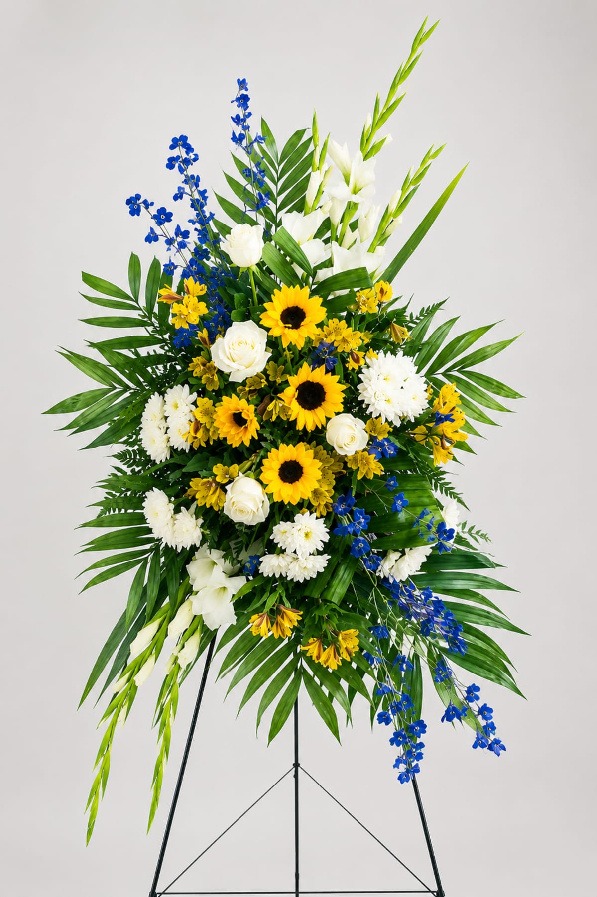 Sunlit standing spray on an easel, delivered by Spring Flower Market to Klein Funeral Home - Champions in Spring, TX.