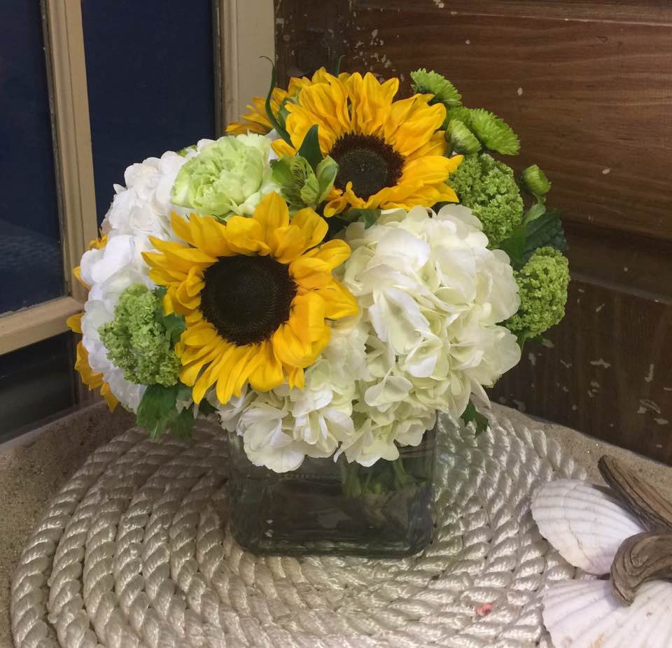 Gorgeous white hydrangea, bright sunflowers and green accents will brighten the gloomiest
