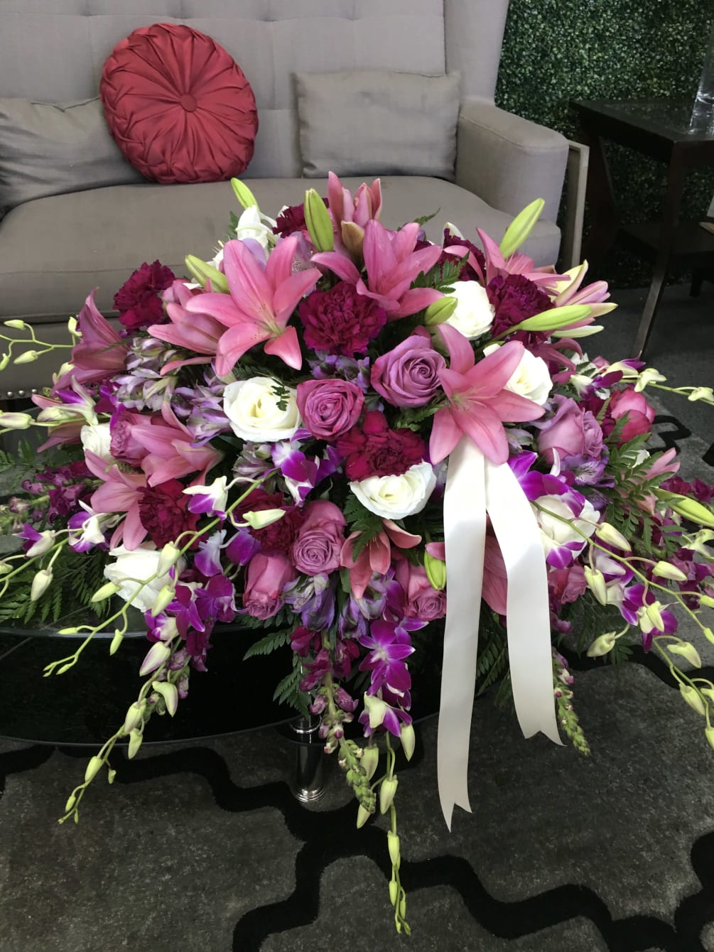 Beautiful casket spray filled with pink lilies, purple carnations, white orchids, iris