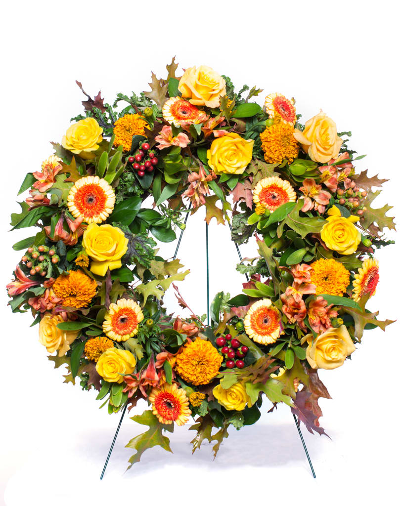 A bright heartwarming wreath with seasonal greens, roses, gerberas, and alstroemeria. Overall
