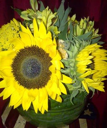 Sunflower centerpiece in a leaf lined vase is sure to brighten anyone&#039;s