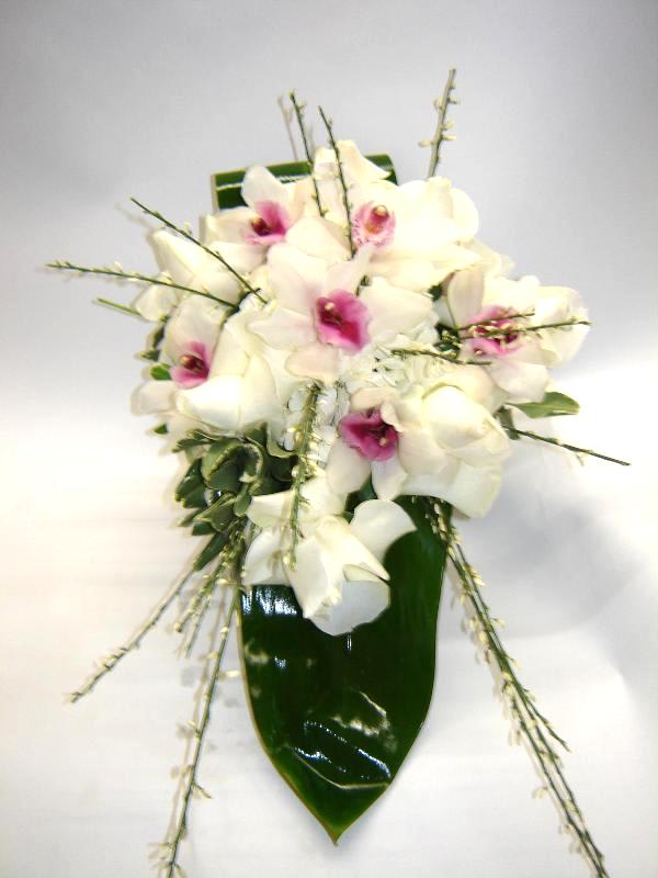 White cymbidium orchids and roses in a simple, yet elegant vase arrangment.