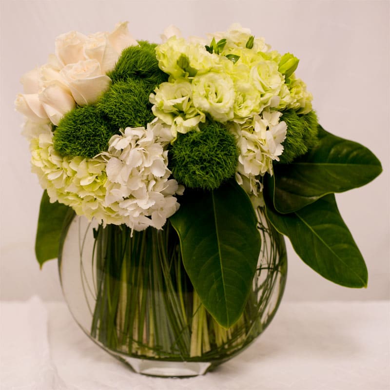 Green and cream-colored roses, white hydrangeas, and white lisianthus blooms with ornamental