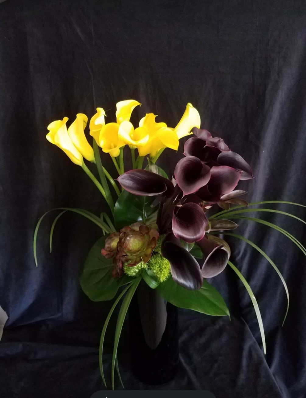 Colored calla lilies with succulents and a variety of greens 