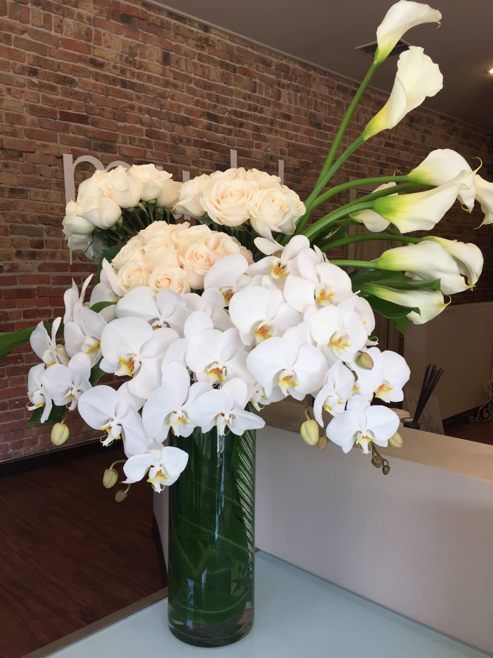 A lush explosion of white flowers to include trumpet calla lilies, rose