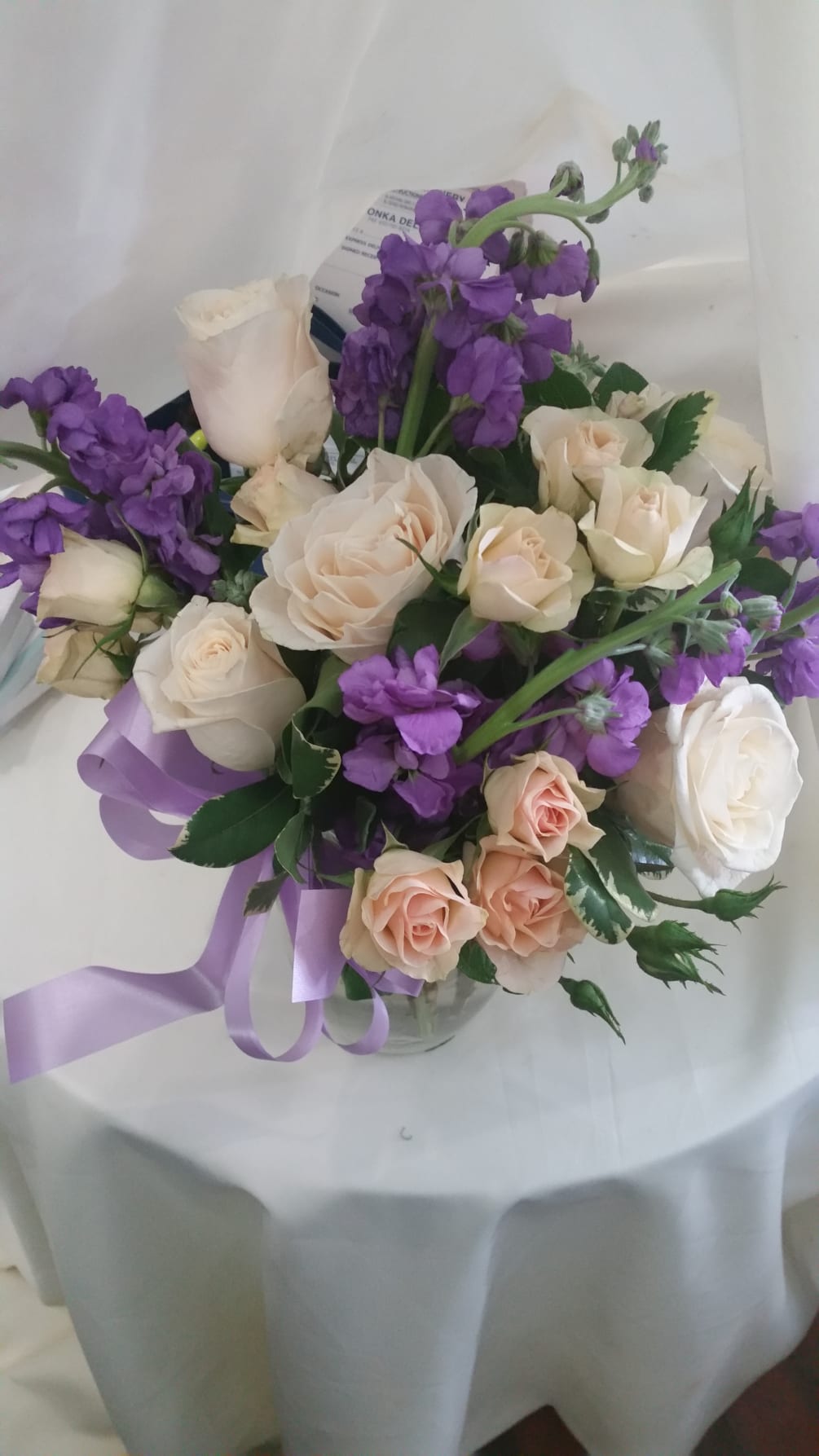Purple snapdragons, peach roses and white roses in a glass vase with