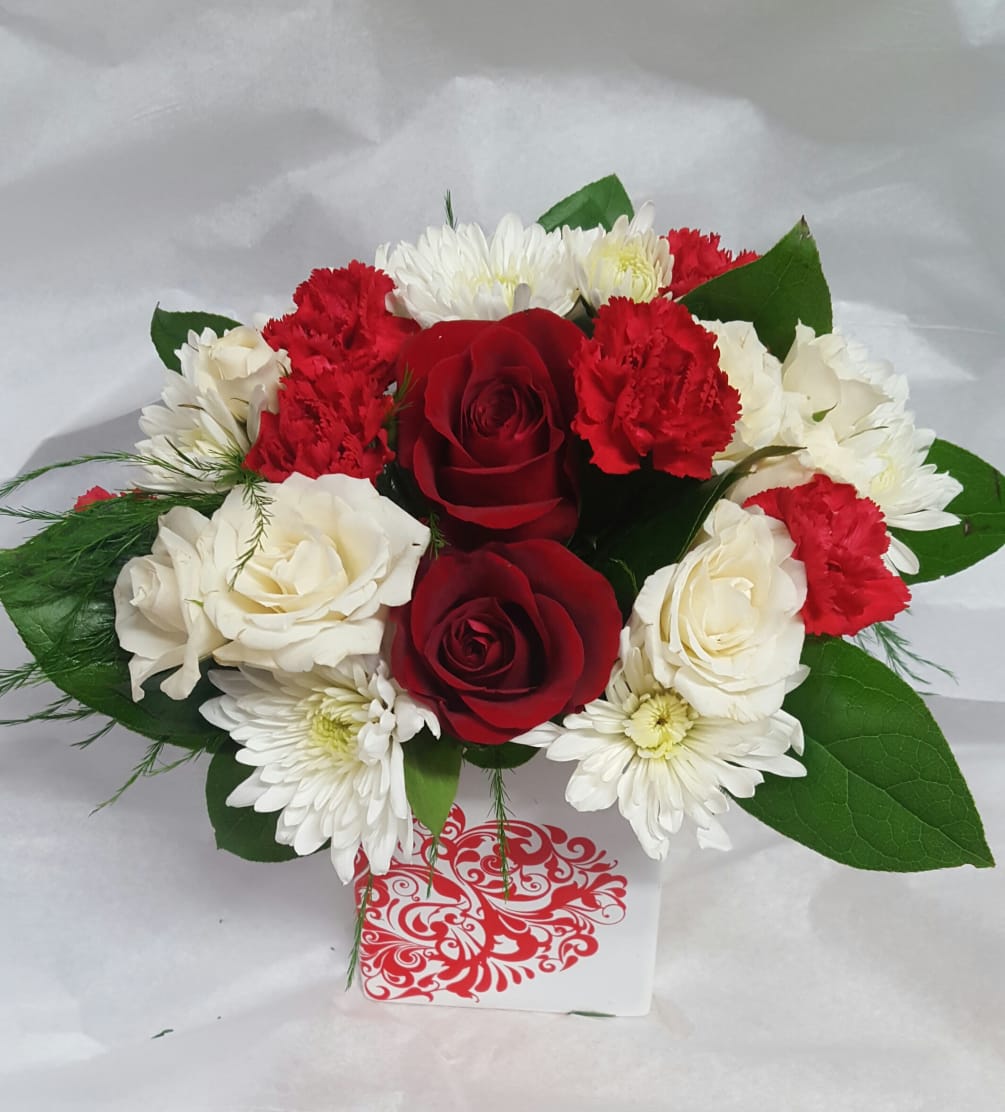 beautifully arranged roses with carnations and spray roses. accented with our heart