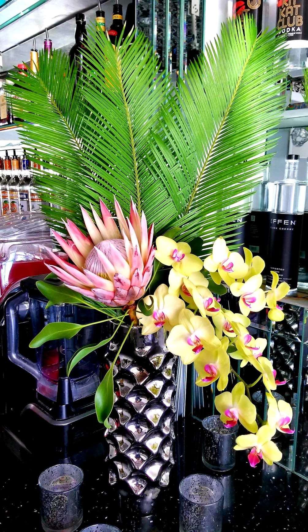 Beautiful assortment of tropical flowers in a tall glass container. 