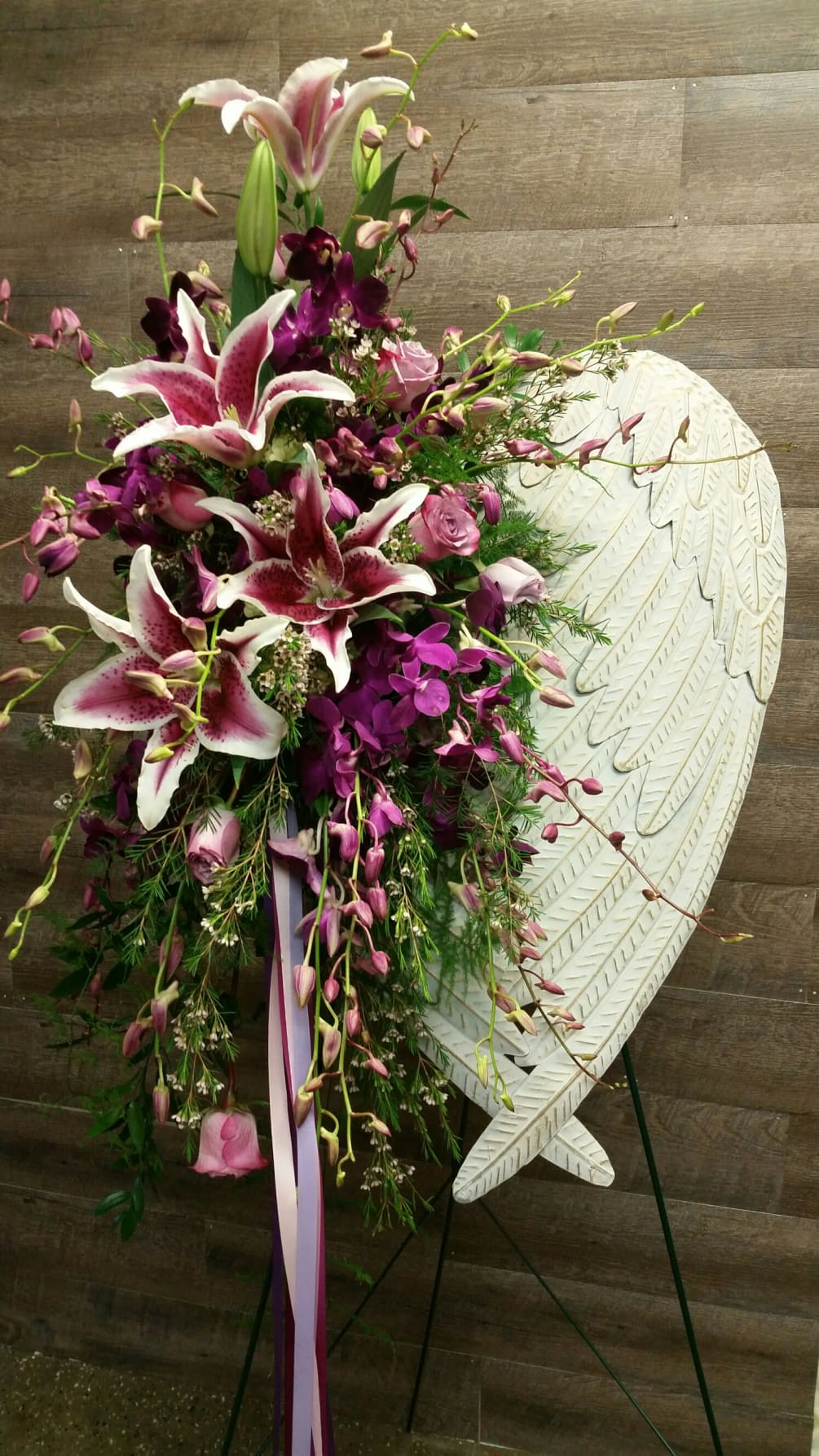 Beautiful stargazer lilies accent a set of white angel wings. Perfect for