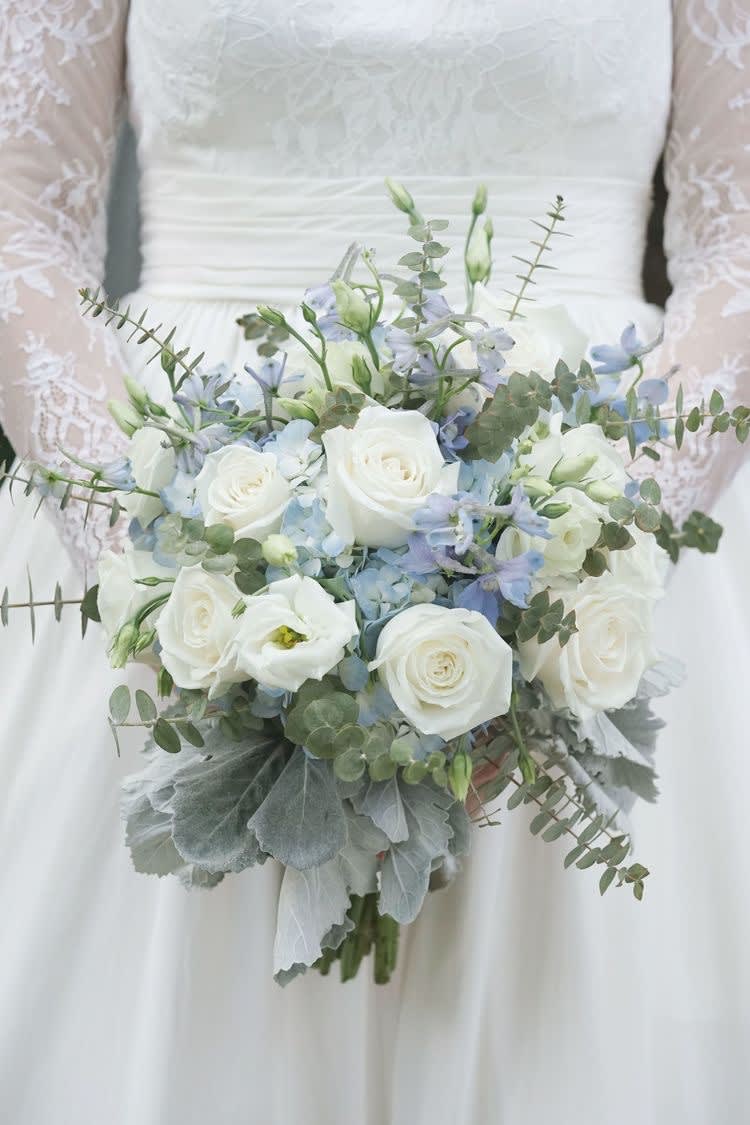 Soft blue delphinium, white roses, white lisianthus and more fill this elegant