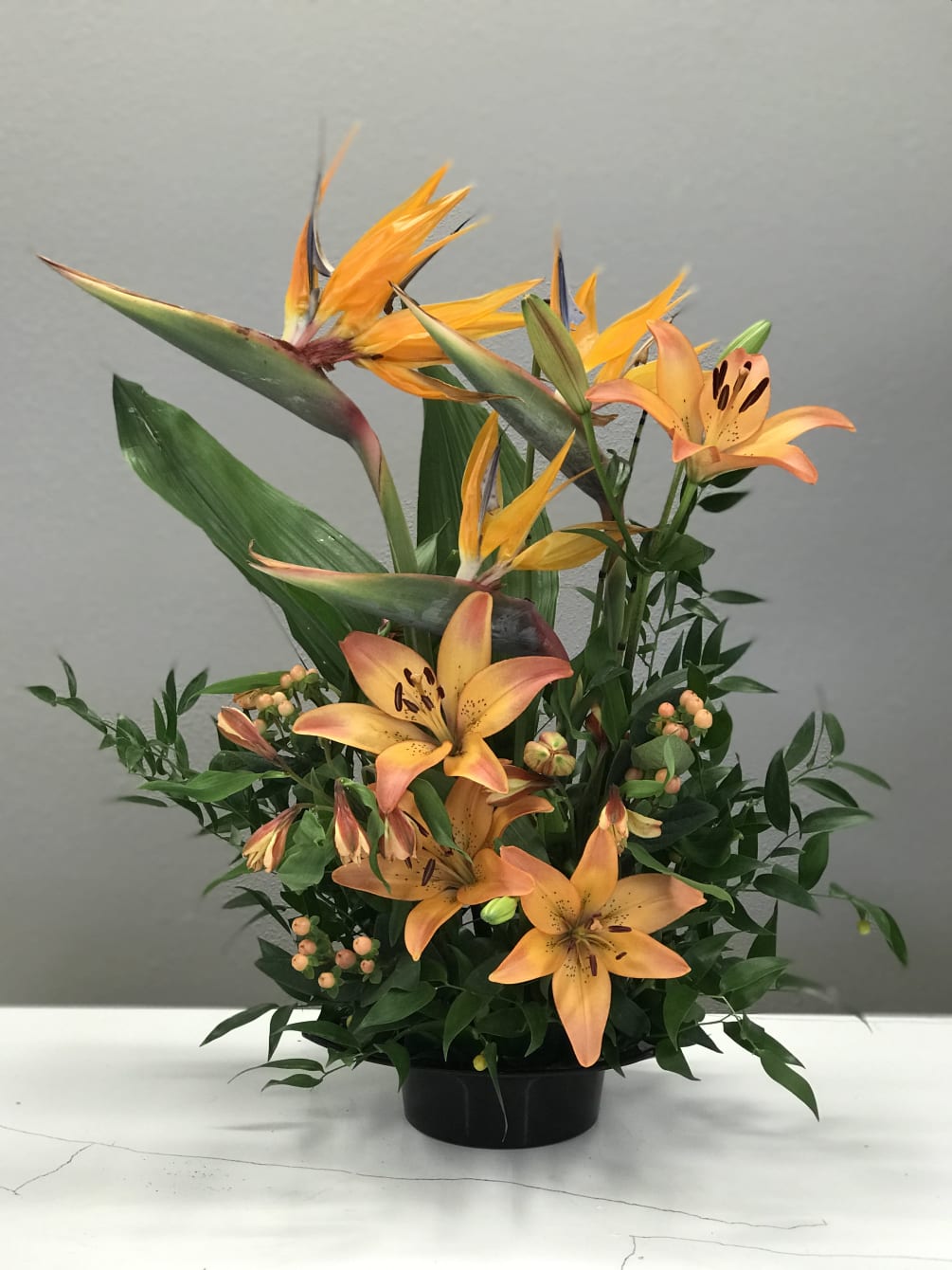 Birds of Paradise rising from orange lilies and a bed a tropical
