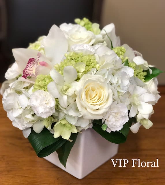 White hydrangeas, cymbidium orchids, white roses, dendrobium orchids, tropical leaves arranged in