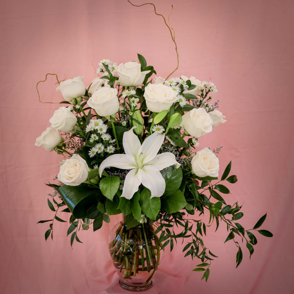 Beautiful arrangement of white long stem roses with a touch of iily.