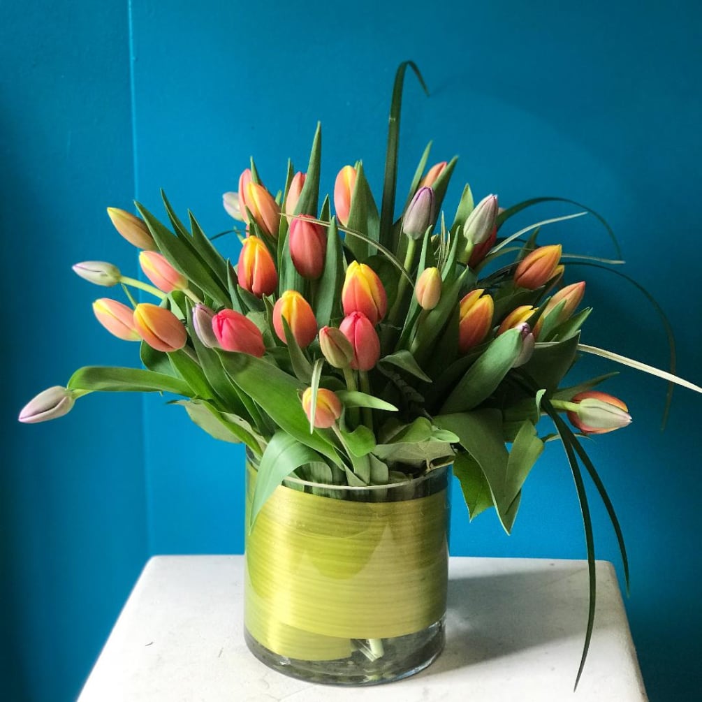 A beautiful vase filled with curly willow inside and beautiful tulips on