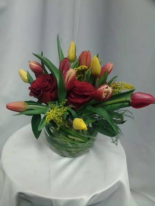 In this picture there are red roses and multi colored tulips with