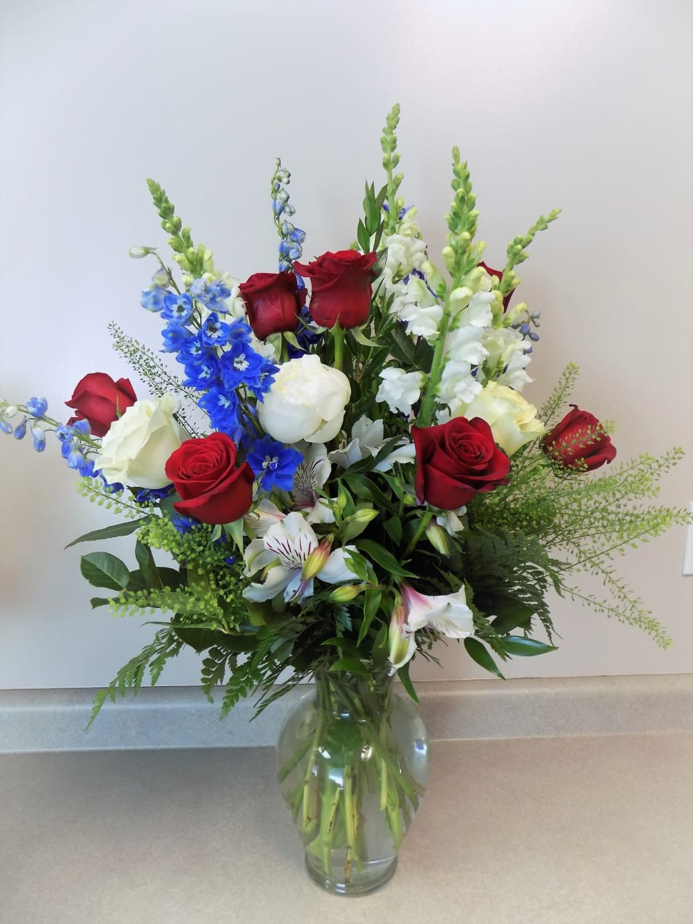 A bouquet brimming with bright blue delphinium, roses, and snapdragons is perfect