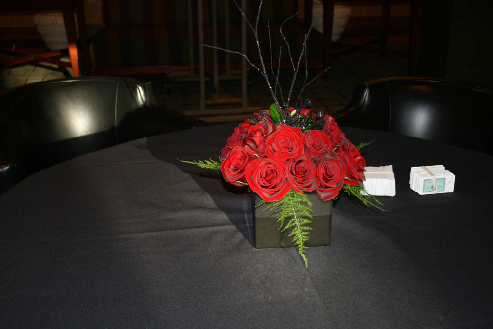 Short centerpiece with one dozen red roses and black top ting- ting