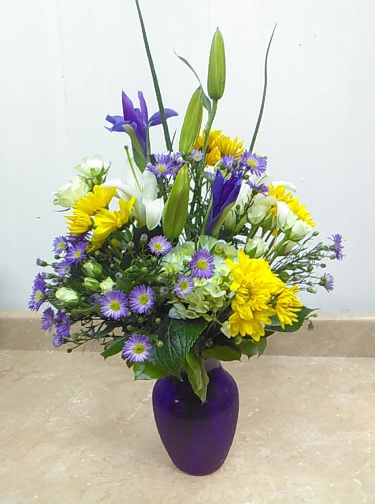 A masterpiece of color that includes White Hydrangea, Purple Iris, White Lilies