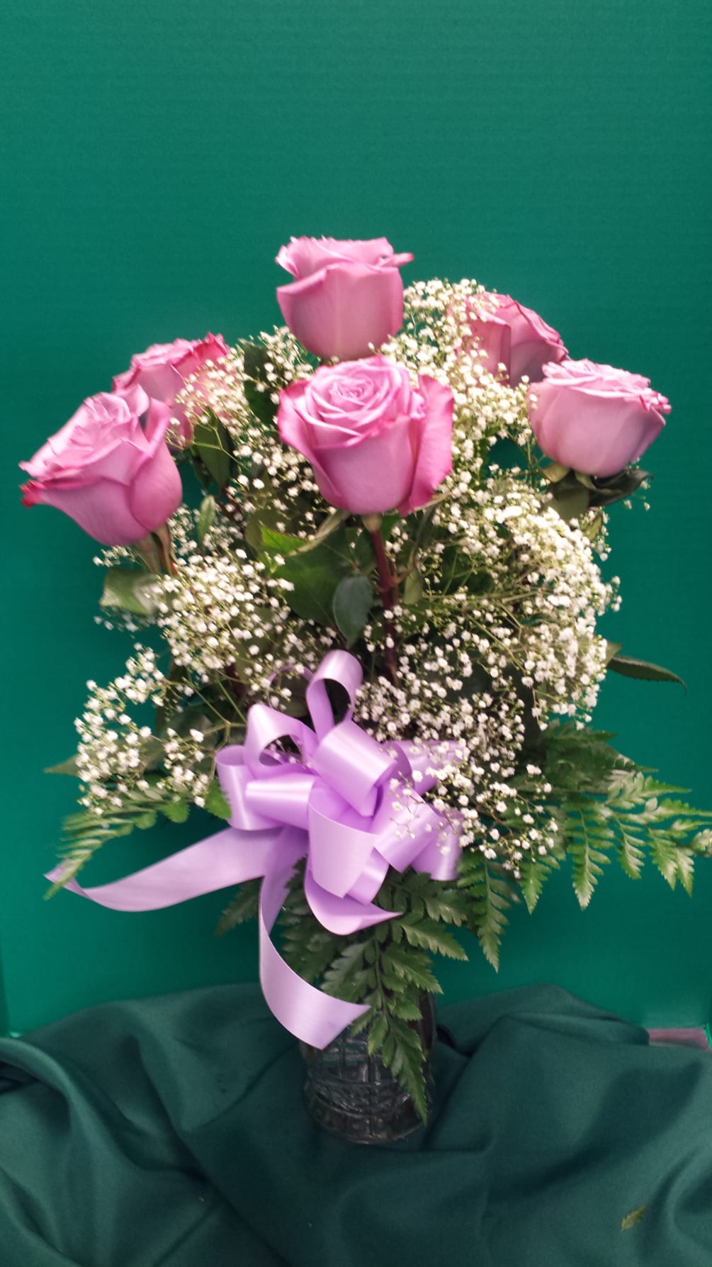 Six long stem roses arranged in a clear vase and accented with