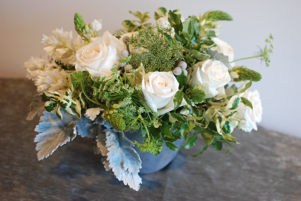 An all white flower bouquet with classical and seasonal flowers and foliage.