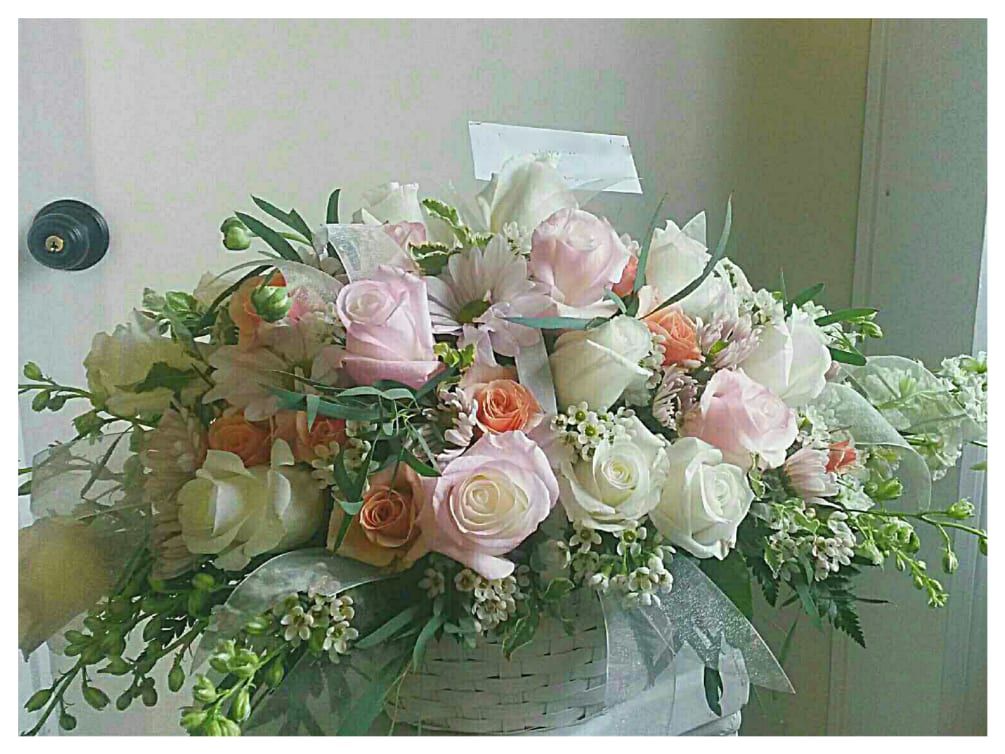 White basket filled with Roses, Spray Roses, Daisies, Delphinium, and various filler.