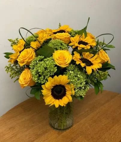 Vibrant Sunflowers, bright yellow roses, fluffy green hydrangea and more are artfully