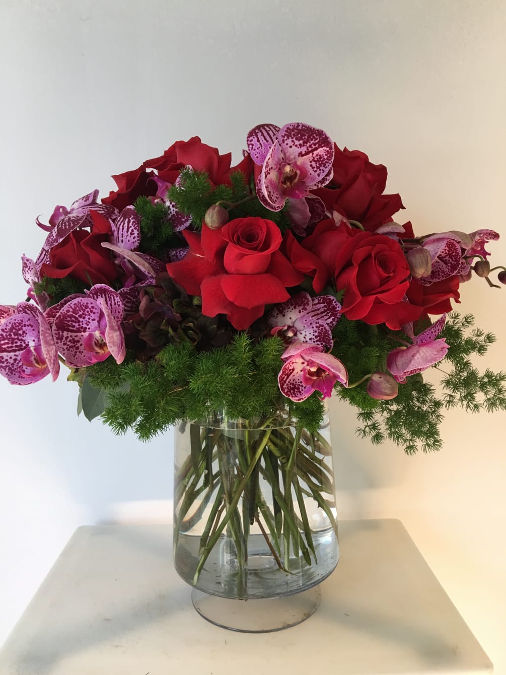 Nice arrangement with red roses and purple orquids nice arrange in a