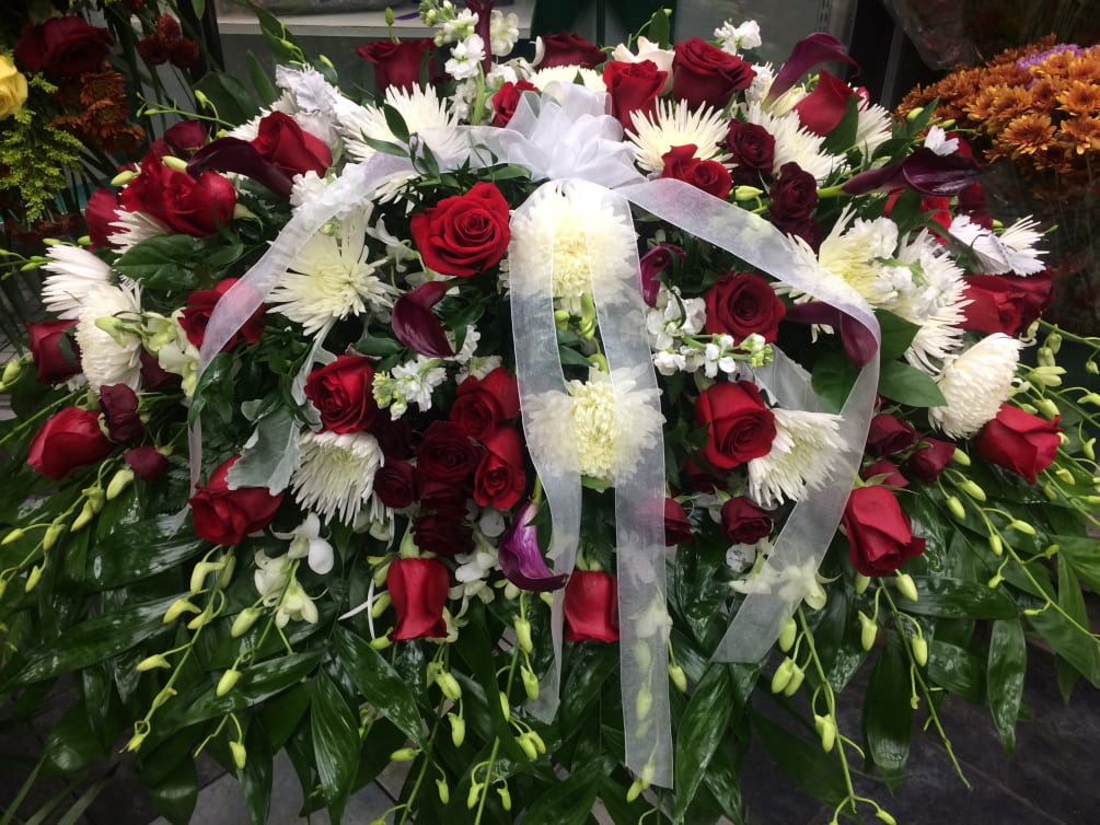 Funeral spray with red roses and white anemone.
