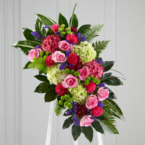 This unique piece features roses, carnations, hydrangea and exotic greenery.  Ribbon