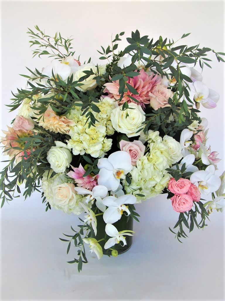 Tall arrangement with lush of seasonal flowers and orchids, matching harmoius colors.