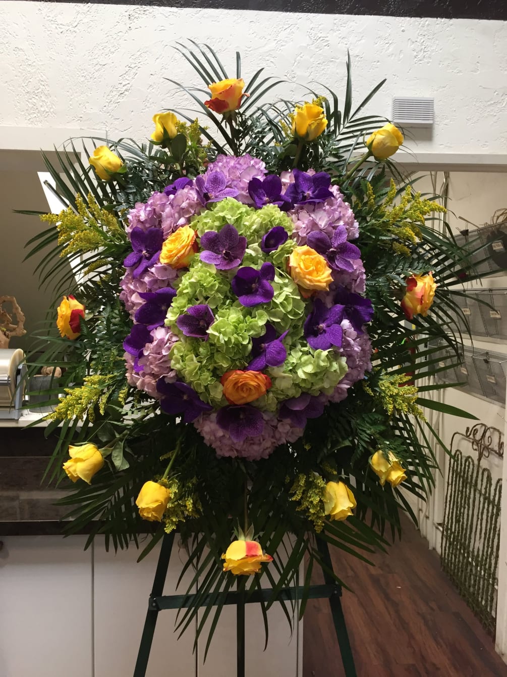 An exquisite spray completed with purple hydrangeas, yellow roses, and purple vanda