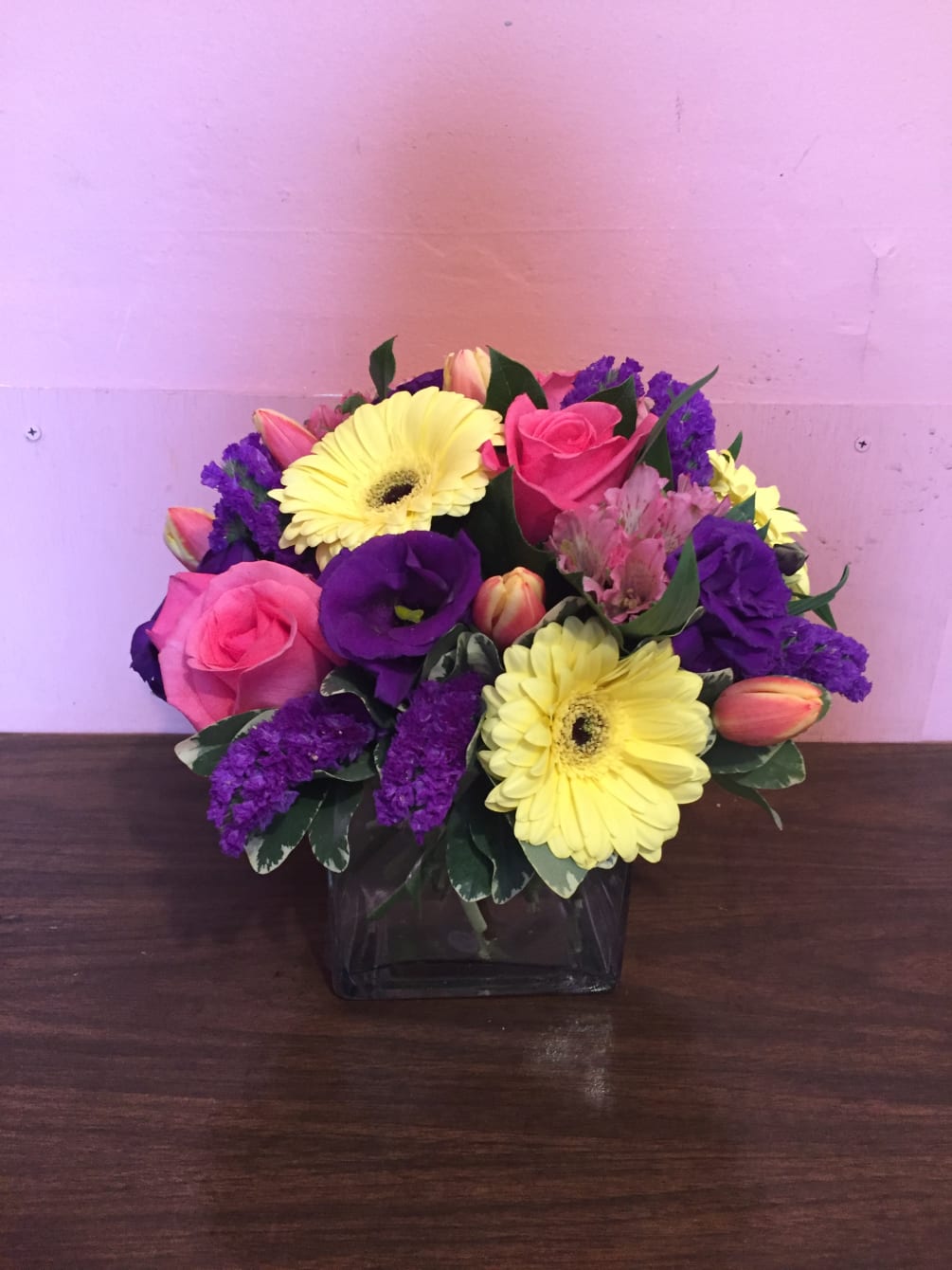 Cube vase with pale yellow gerbera daisy, dark purple lisianthus, purple statice