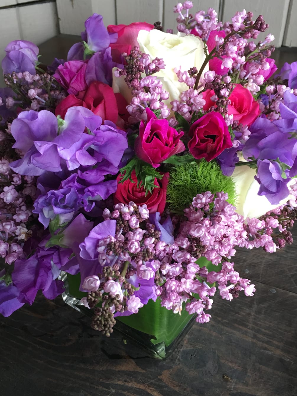 A beautiful spring mix of sweet peas, lilacs, anemones, roses, dianthus wrapped
