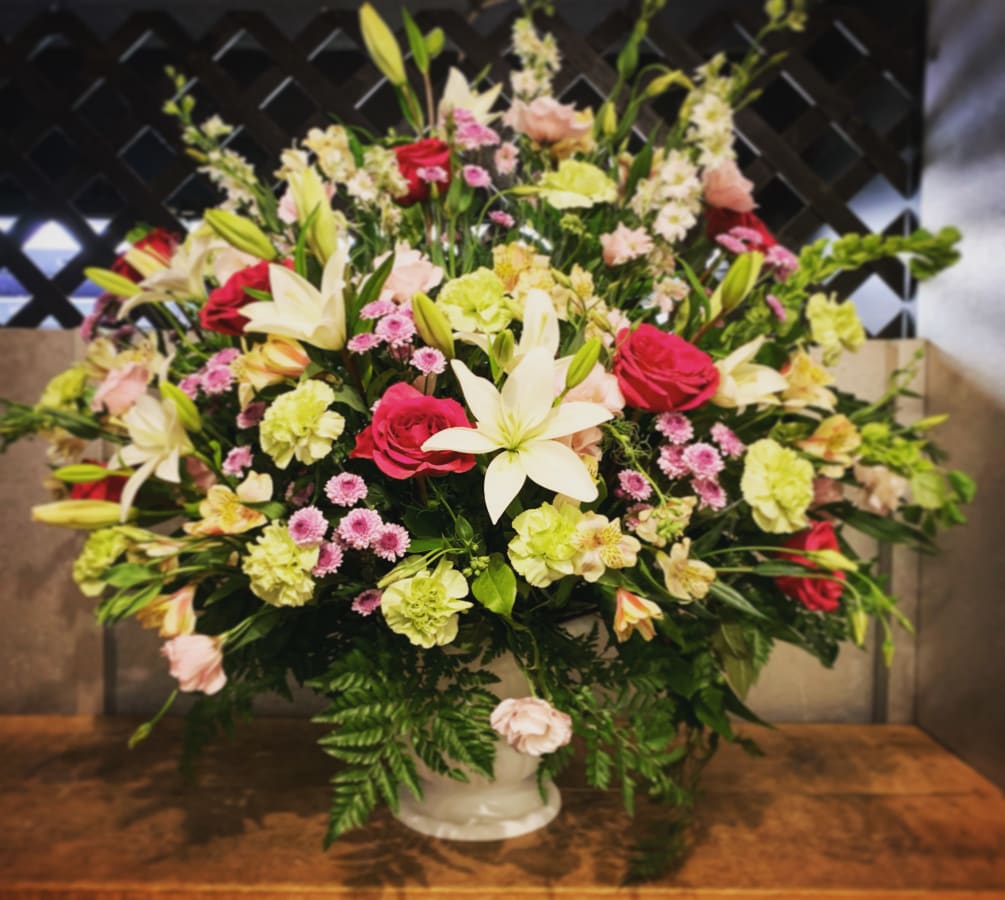 A large funeral basket of elegant hues of white, pink, and peach