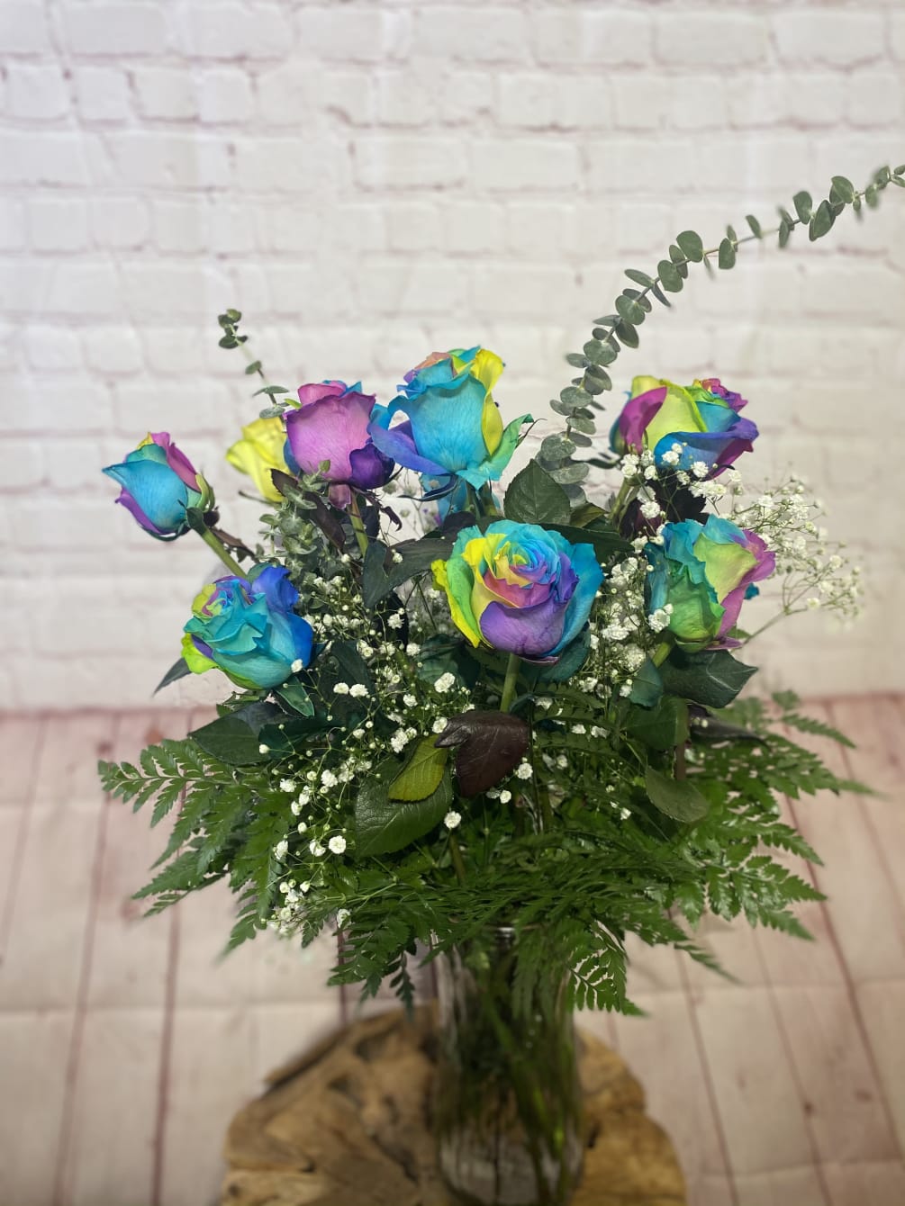 12 long stem rainbow dyed roses with greenery and baby breath. A