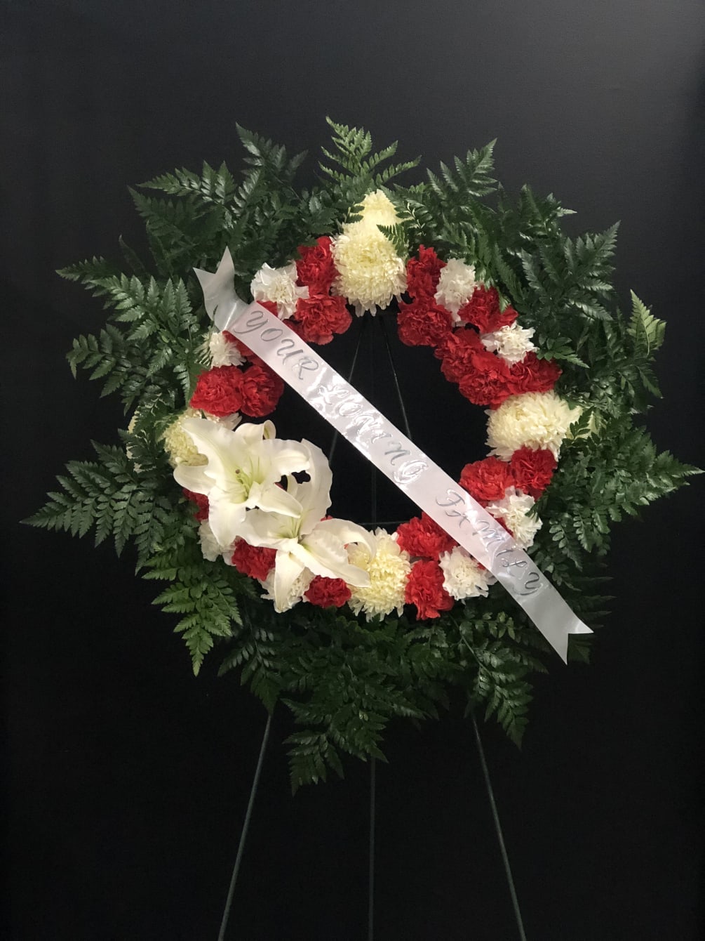 The circle of carnations with red and white with a white ribbon.
