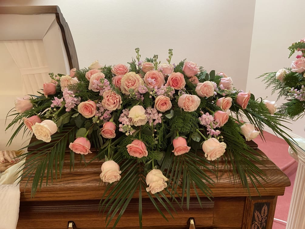Shades of pink roses in a full couch casket spray.