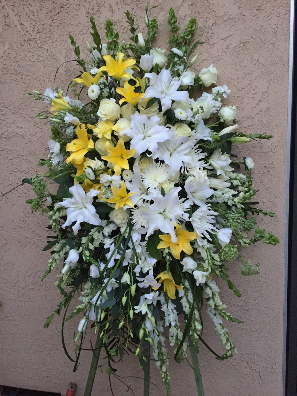 Standing spray including yellow and white flowers.